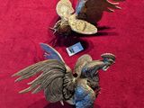 two figurines of birds on display on a red surface