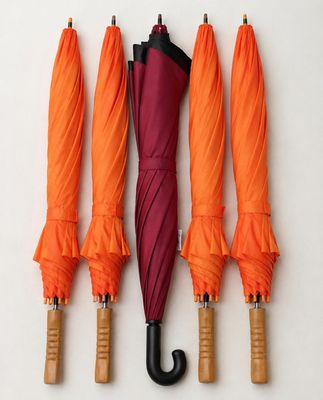 four umbrellas are lined up against a white wall with a wooden handle