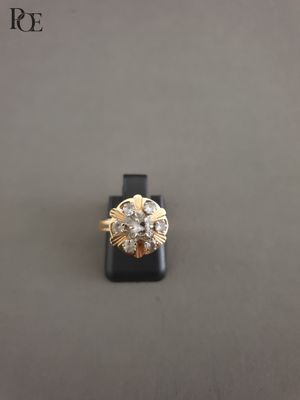 un gros plan d'une bague en or sertie de diamants, posée sur un socle noir