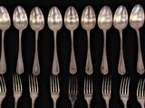 a lot of silver spoons and forks on a black background
