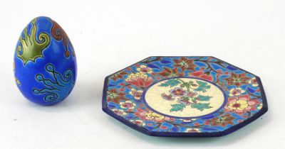 une assiette bleue et un œuf bleu posés l'un à côté de l'autre