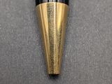 a close up of a black and gold pen on a gray surface
