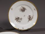two plates with gold rims and flowers on them on a table
