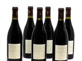 six bottles of wine are lined up in a row on a white surface