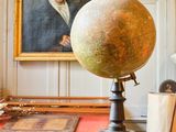 un grand globe terrestre posé sur un bureau, devant un tableau