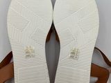 a pair of white sandals with brown straps on a white surface