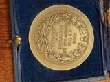 a gold medal in a blue box on a wooden table