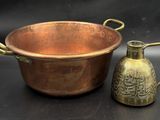a copper pot and a brass jug on a black background