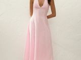 une femme en robe rose posant pour une photo devant un mur blanc