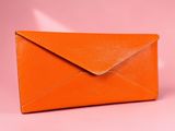an orange envelope on a pink background