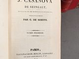a book open on a table with many books in the background