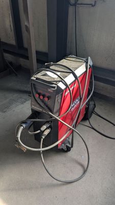 une machine rouge et noire à laquelle est raccordé un tuyau