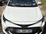 l'avant d'une Toyota Corolla blanche garée sur le bord de la route