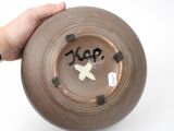 a person holding a brown bowl with writing on it