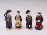 three figurines of people dressed in traditional clothing standing next to each other