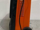 an orange and black machine sitting on top of a floor next to a white wall