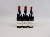 three bottles of red wine sitting next to each other on a white surface