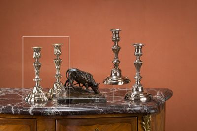 trois bougies en argent posées sur une table au plateau en marbre