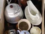une boîte remplie de théières et de tasses posée par terre