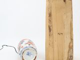 a wooden block with a vase on it next to a lamp