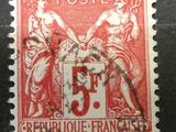 un vieux timbre rouge et blanc sur lequel figure l'image d'une femme