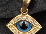 un gros plan sur un pendentif en or orné d'un œil bleu