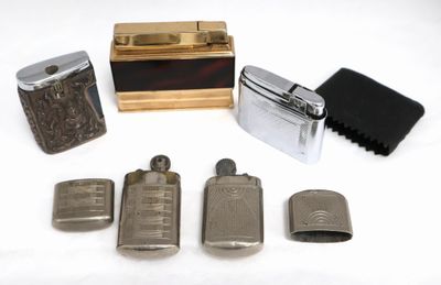 quatre briquets et un étui à briquets posés sur une surface blanche