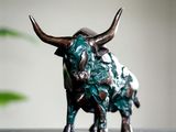 une statue de taureau posée sur une table, à côté d'une plante en pot