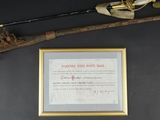an old gun and a framed certificate are on a table