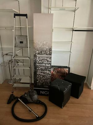 une pièce avec une échelle, une chaise, une bibliothèque et un aspirateur posé par terre