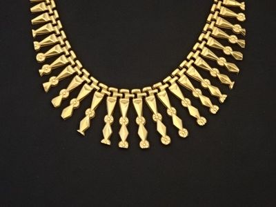 un collier en or posé sur une surface noire, avec un fond noir
