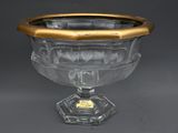 un bol en verre ancien, orné d'une bordure dorée, trône sur un socle