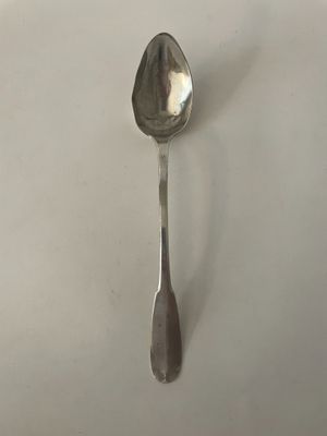 une cuillère en argent posée sur une surface blanche, d'où dépasse une petite cuillère