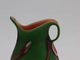 a green vase with a red stripe on it