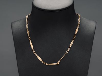 a black mannequin torso with a gold chain necklace on it