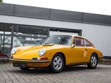 yellow porsche 911 parked in front of a building with a car in the background