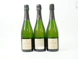 trois bouteilles de vin posées les unes à côté des autres sur une surface blanche