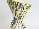 a yellow and black vase sitting on a white surface
