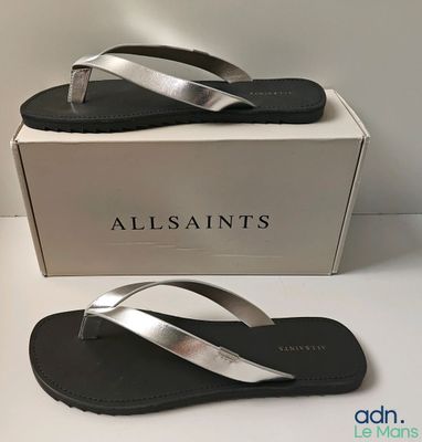 the box is white and has a pair of silver sandals on it