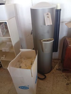 a trash can and a water heater in the corner of a room