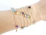 a woman ' s arm with five different colored bracelets on it