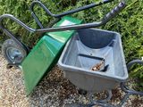 a green wheelbarrow and a black wheelbarrow on a gravel path
