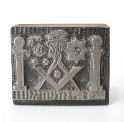 une image représentant une plaque métallique sur laquelle figure un symbole maçonnique