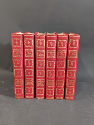 six red books lined up in a row on a gray surface