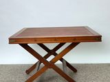 une table en bois aux deux pieds entrecroisés, posée sur un sol recouvert de moquette