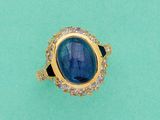 gros plan d'une bague avec une pierre bleue entourée de diamants