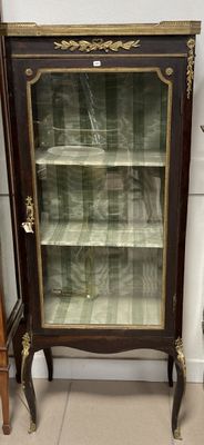 une vitrine aux portes vitrées, placée dans un coin de la pièce