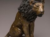 bronze statue of a lion sitting on its hind legs