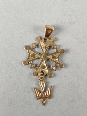 a close up of a gold cross pendant on a white surface