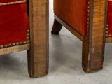 pair of red velvet upholstered chairs with wooden legs and studding